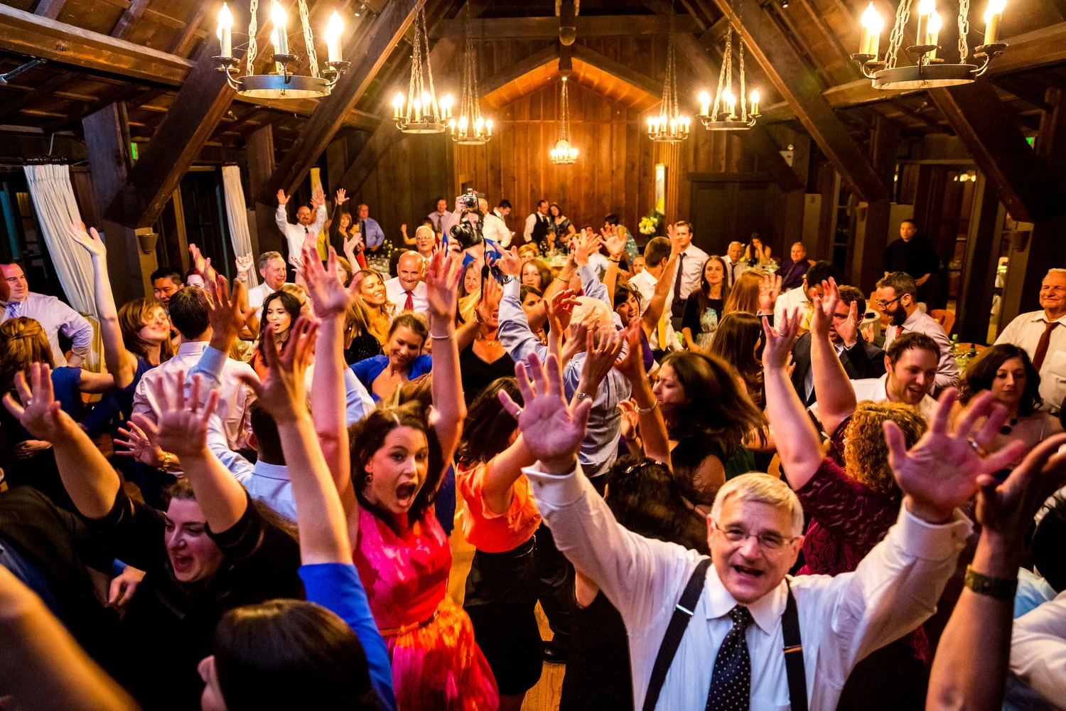 Packed wedding dance floor with hands in the air